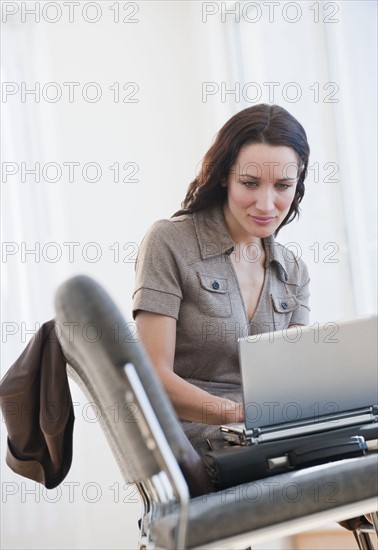 Businesswoman using laptop in waiting room.