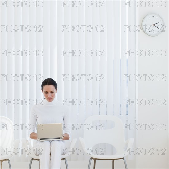 Businesswoman using laptop in waiting room.