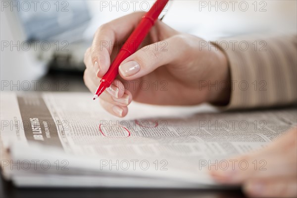 Woman circling classfields, close-up.