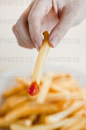 Woman with french fries, close-up of hand.