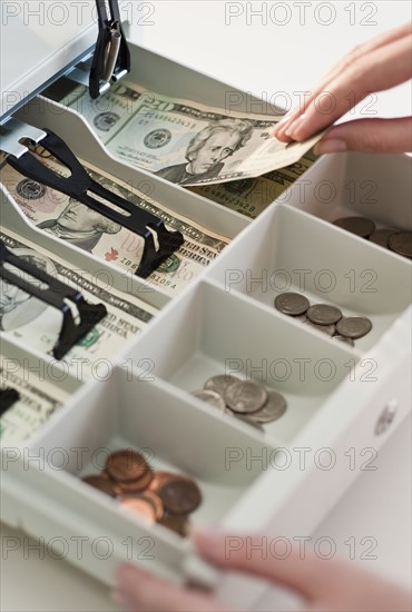 Woman removing money from cash register, close-up.