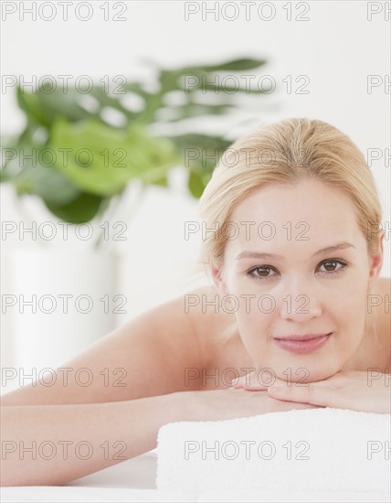 Young woman lying on front and waiting for massage, portrait. Photographe : Jamie Grill