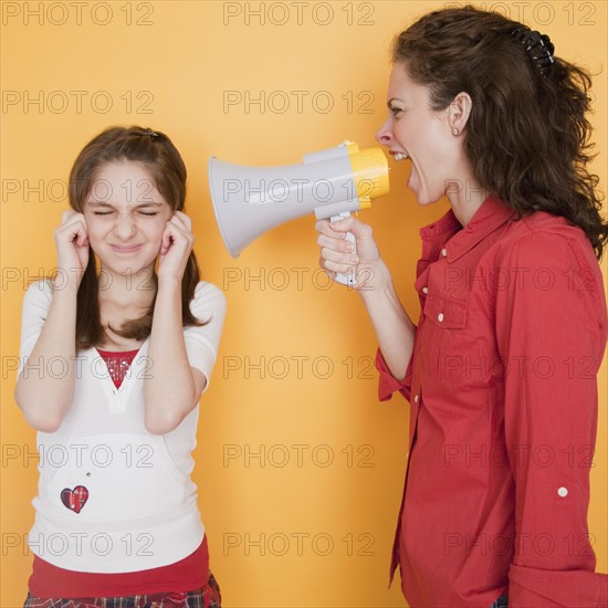 Mother yelling at daughter (10-12 years) through megaphone. Photographe : Jamie Grill