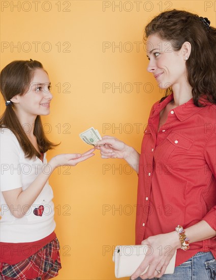 Mother giving daughter (10-12 years) pocket money. Photographe : Jamie Grill