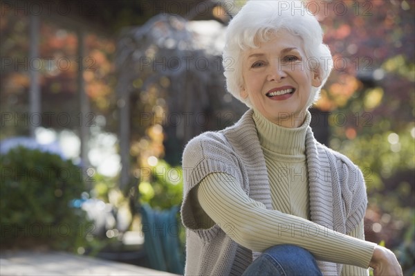 Portrait of senior woman sitting in garden. Photographe : mark edward atkinson