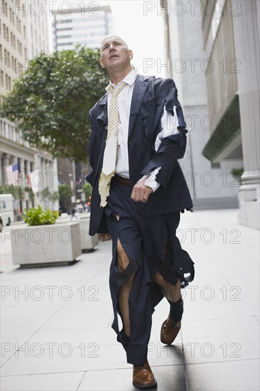 Businessman wearing torn clothing, walking in street, San Francisco, California, USA. Photographe : PT Images