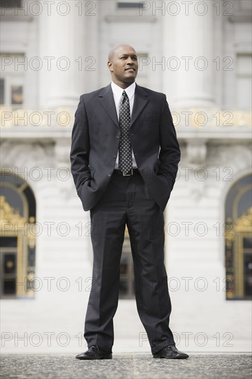 Businessman standing outside office building, San Francisco, California, USA. Photographe : PT Images