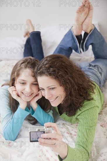 Mother and daughter (10-12 years) photographing self with digital camera. Photographe : Jamie Grill