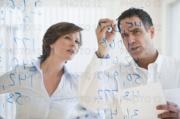 Mature businesswoman and businessman making calculations.