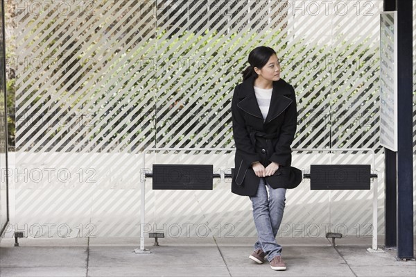 Young woman waiting at bus stop, San Francisco, California, USA. Photographe : PT Images