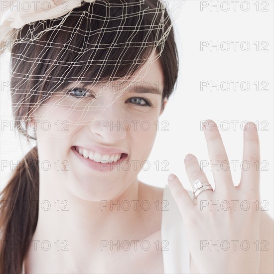 Portrait of bride wearing wedding dress, showing ring. Photographe : Jamie Grill