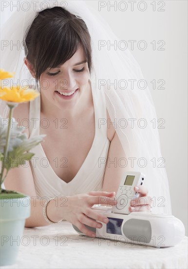 Bride holding speakers of stereo, studio shot. Photographe : Jamie Grill