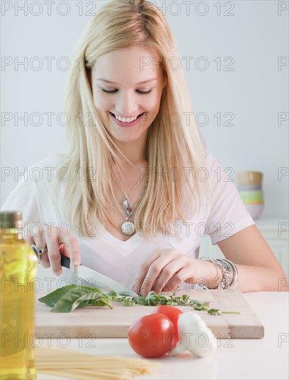 Young woman chopping basil. Photographe : Jamie Grill