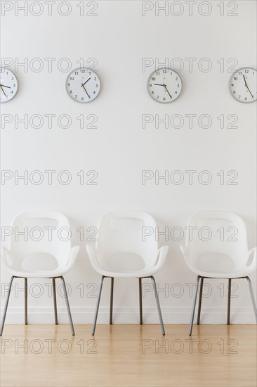 Row of chairs in waiting room under clocks displaying time zones.