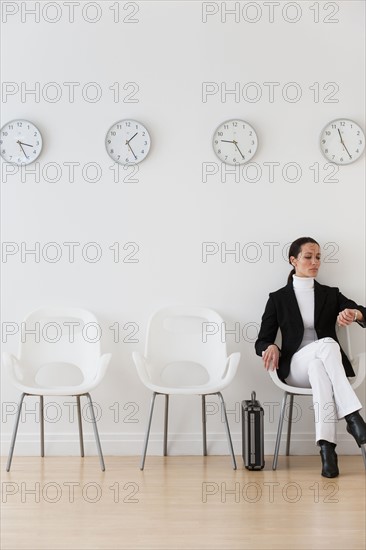 Businesswoman looking at wrist watch in waiting room.