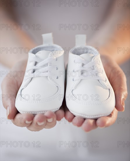 Close-up of woman holding baby shoes.