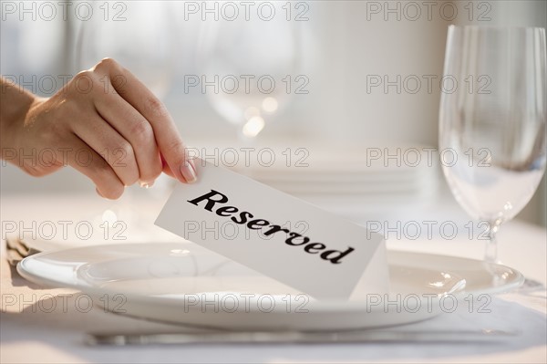 Woman placing tag on restaurant table, close-up.