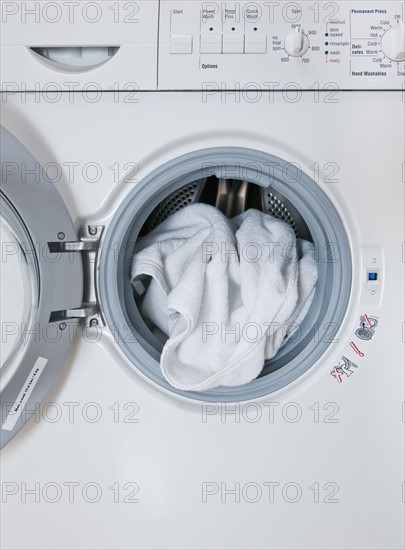 Washing machine with laundry sticking out, close-up.