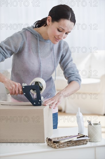 Woman preparing parcel, smiling.