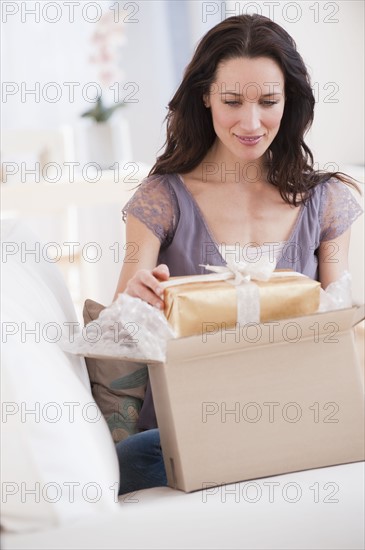 Woman unpacking parcel with present, smiling.
