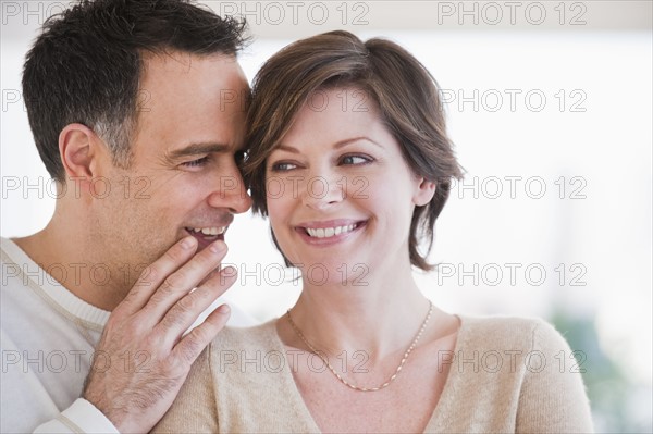 Man whispering to woman's ear.