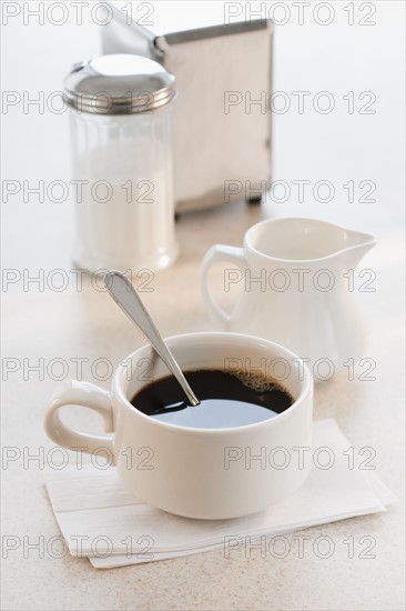 Cup of coffee with milk and sugar on table.