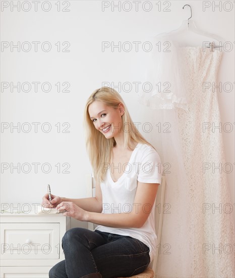 Portrait of young woman writing wedding invitation. Photographe : Jamie Grill