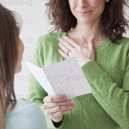 Mother receiving greeting card on mother's day from daughter (10-12 years). Photographe : Jamie Grill