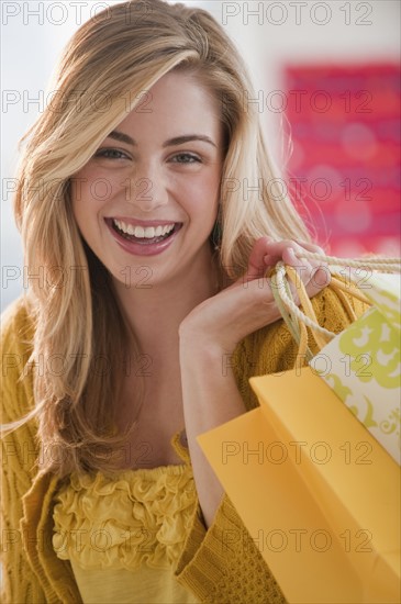 Portrait of young woman holding shopping bags in shop. Photographe : Daniel Grill