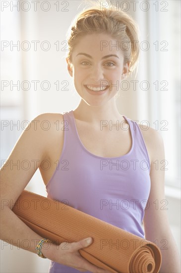 Portrait of young woman holding exercise mat. Photographe : Daniel Grill