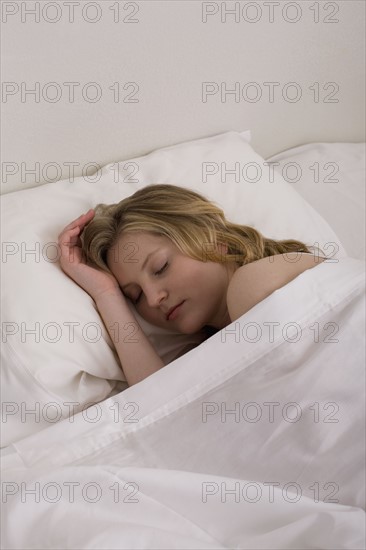 Young woman sleeping in bed. Photographe : David Engelhardt
