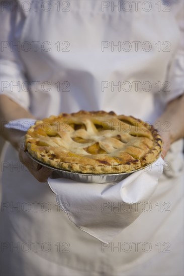 Senior woman holding freshly baked pie. Photographe : mark edward atkinson