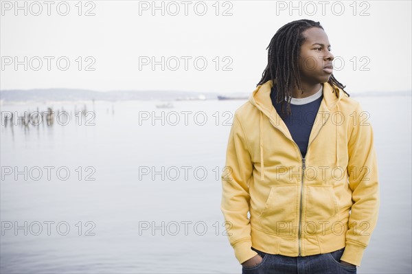 Teenage boy (16-17) with dreadlocks, standing at waterfront, San Francisco, California, USA. Photographe : PT Images