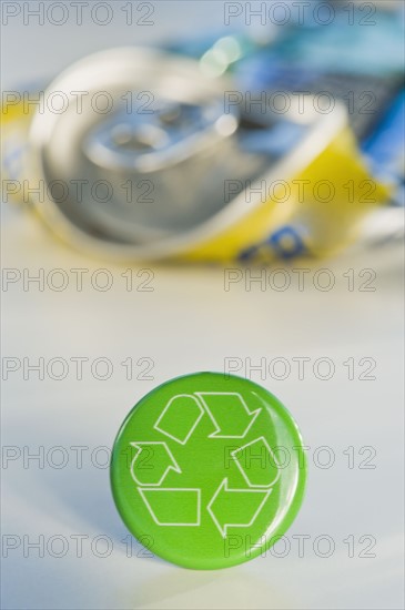 Recycling sign with crushed can, studio shot. Photographe : Daniel Grill