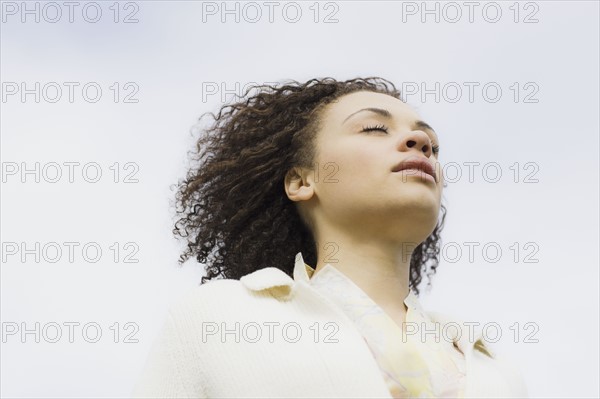 Young woman with eyes closed, outdoors. Photographe : PT Images