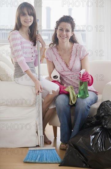 Mother and daughter (10-12 years) preparing to clean house, smiling, portrait. Photographe : Jamie Grill