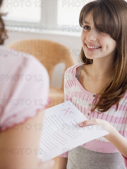 Daughter (10-12 years) showing mother essay result. Photographe : Jamie Grill