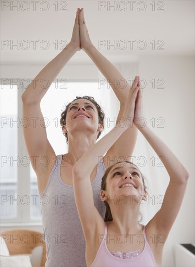 Mother and daughter (10-12 years) doing yoga. Photographe : Jamie Grill