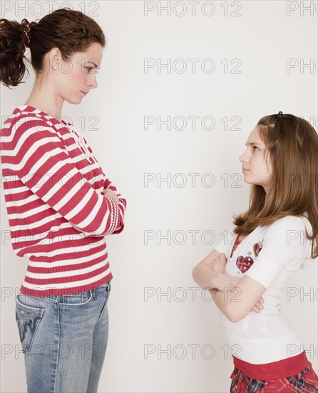 Mother and daughter (10-12 years) having argument, standing face to face. Photographe : Jamie Grill