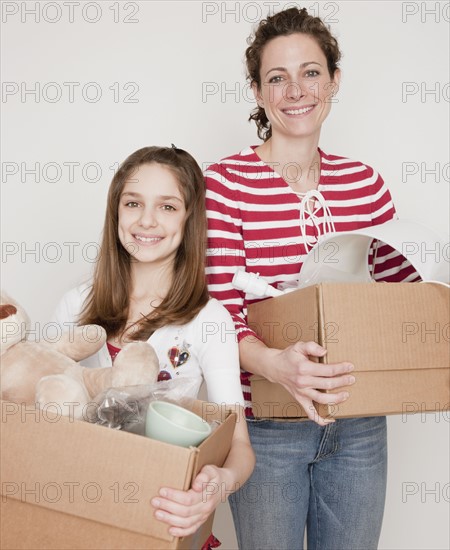 Mother and daughter (10-12 years) preparing to moving out, portrait. Photographe : Jamie Grill