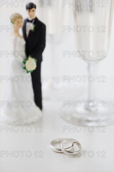 Wedding rings by bride and groom cake toppers and wineglasses. Photographe : Jamie Grill