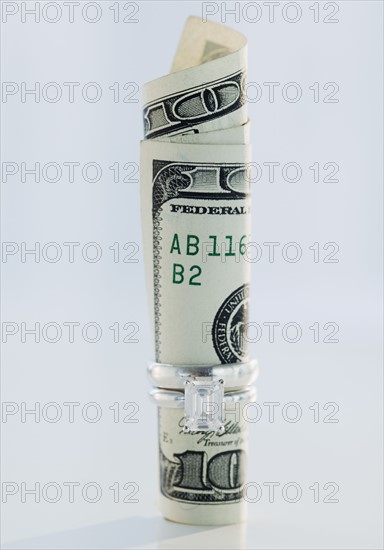 One hundred dollar bill rolled up in wedding ring. Photographe : Jamie Grill