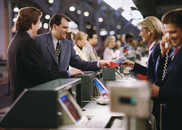 Businessman buying ticket at the airport. Photographe : Stewart Cohen