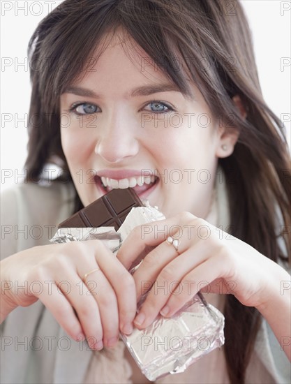 Portrait of young woman eating chocolate. Photographe : Jamie Grill