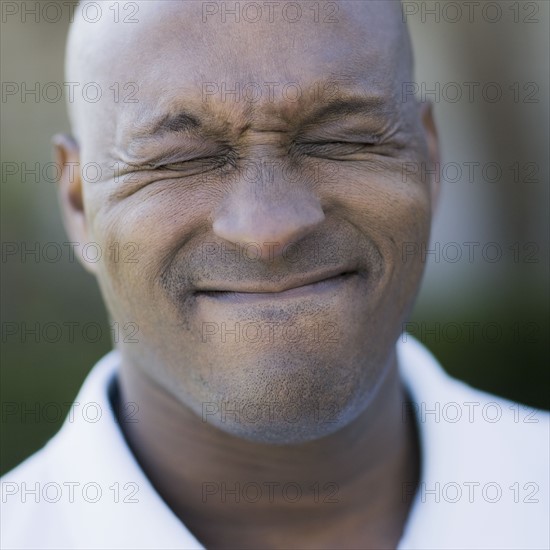 Portrait of man grimacing, close-up. Photographe : PT Images