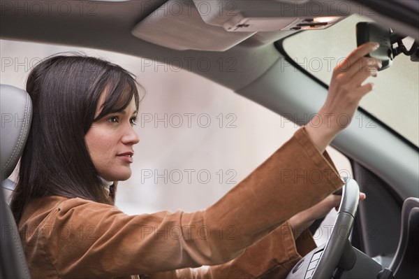 Woman adjusting rear view mirror.