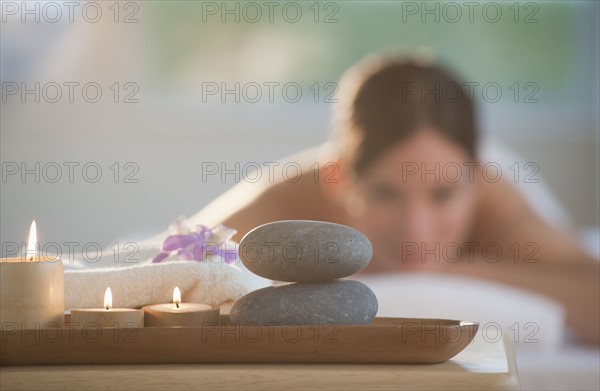 Rocks and candles on tray with woman lying in background.