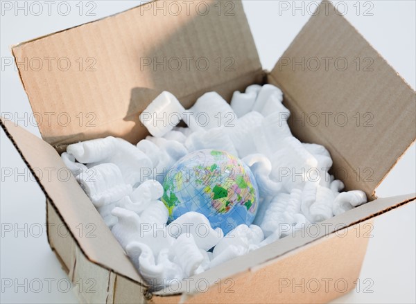 Globe in cardboard box with packing peanuts. Photographe : Jamie Grill