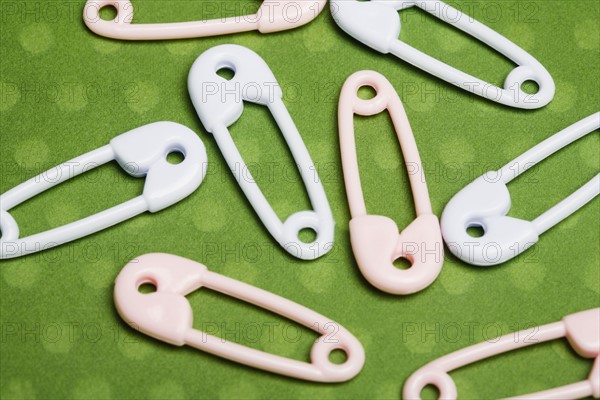 Safety pins on green background. Photographe : Kristin Lee