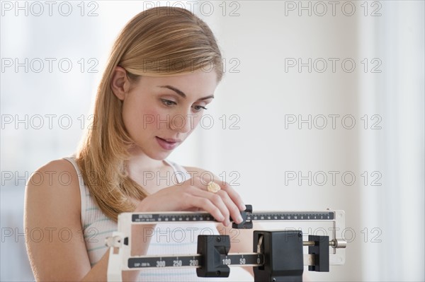 Young woman using measuring scales. Photographe : Daniel Grill